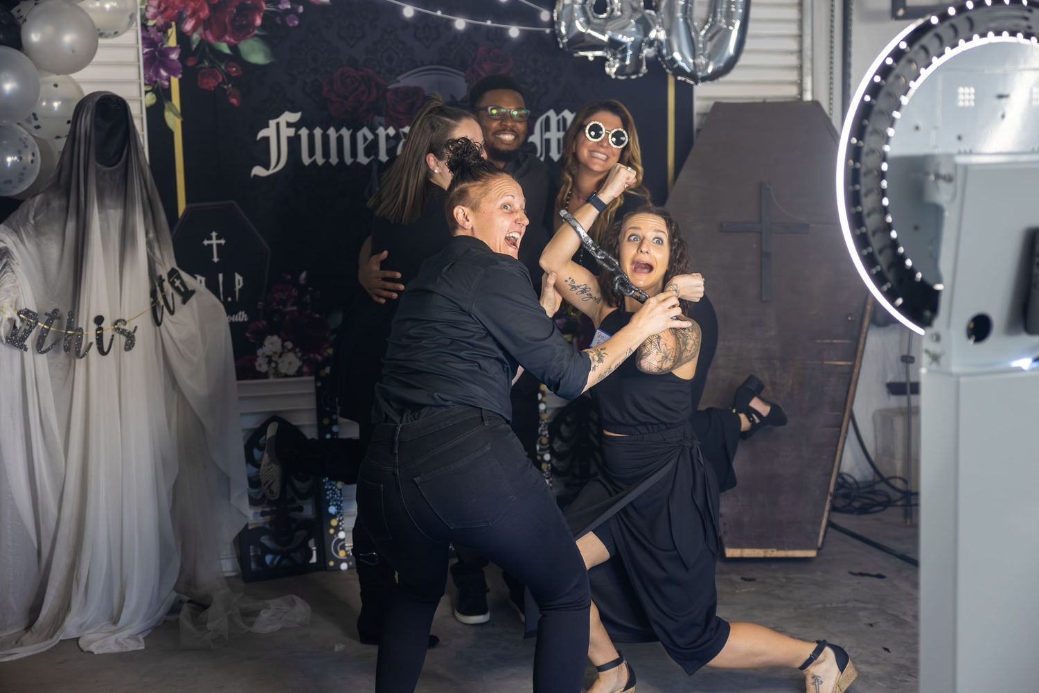 group of people in front of photo booth with props posing for a photo
