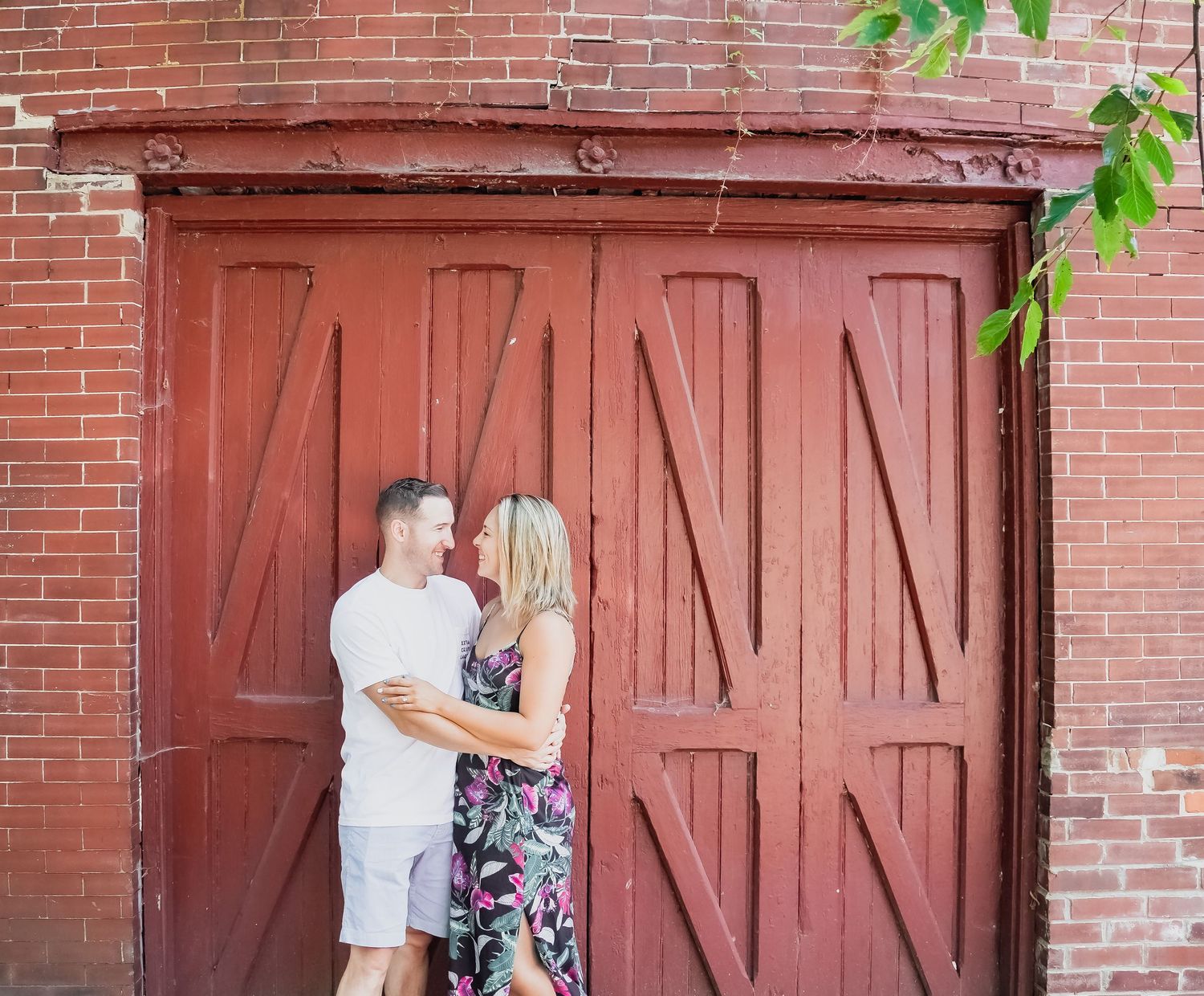 A couple sharing an intimate moment against a vintage red barn door.