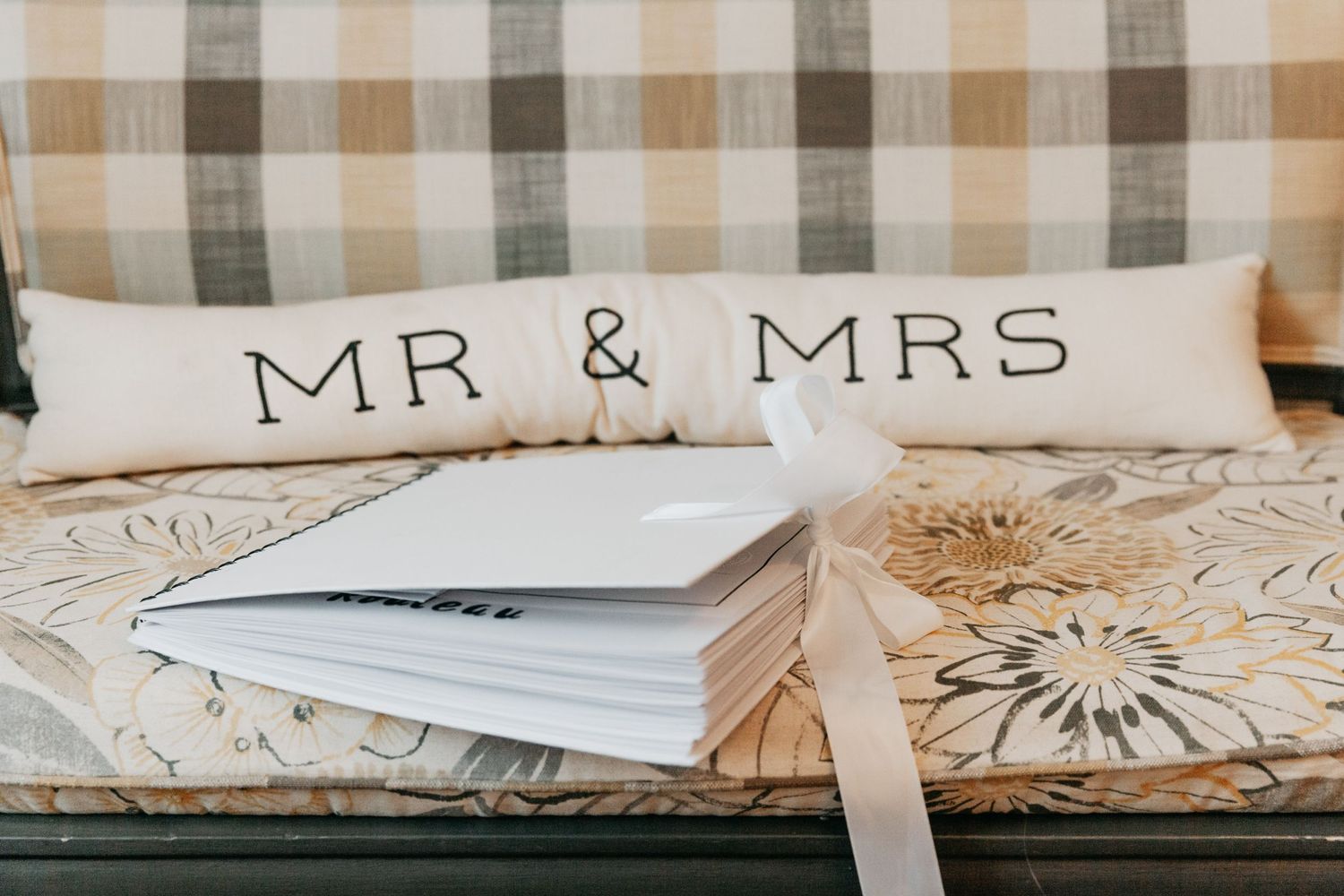 Mr and Mrs decorative pillows on a bench with a white wedding guest book.