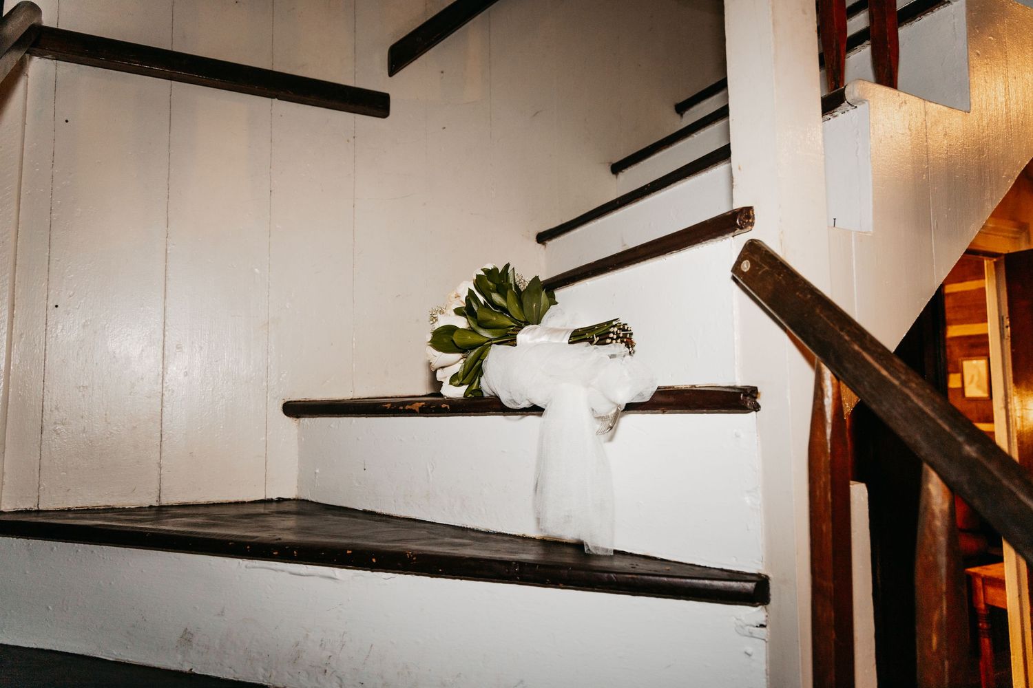 A green succulent plant in a white vase decorates rustic wooden stairs with white painted walls.