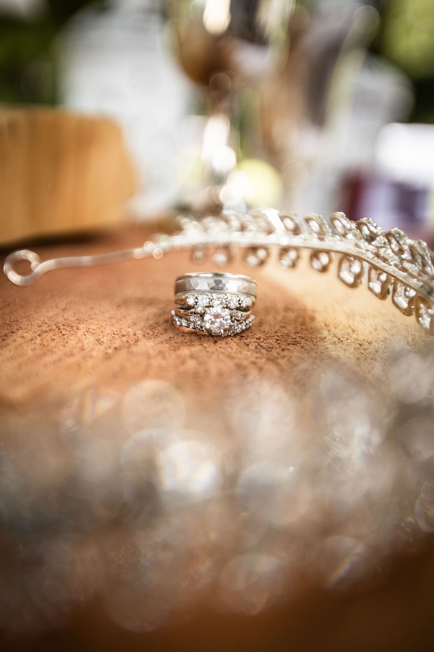 Diamond wedding ring set displayed on golden surface beside sparkling tiara wedding accessories.