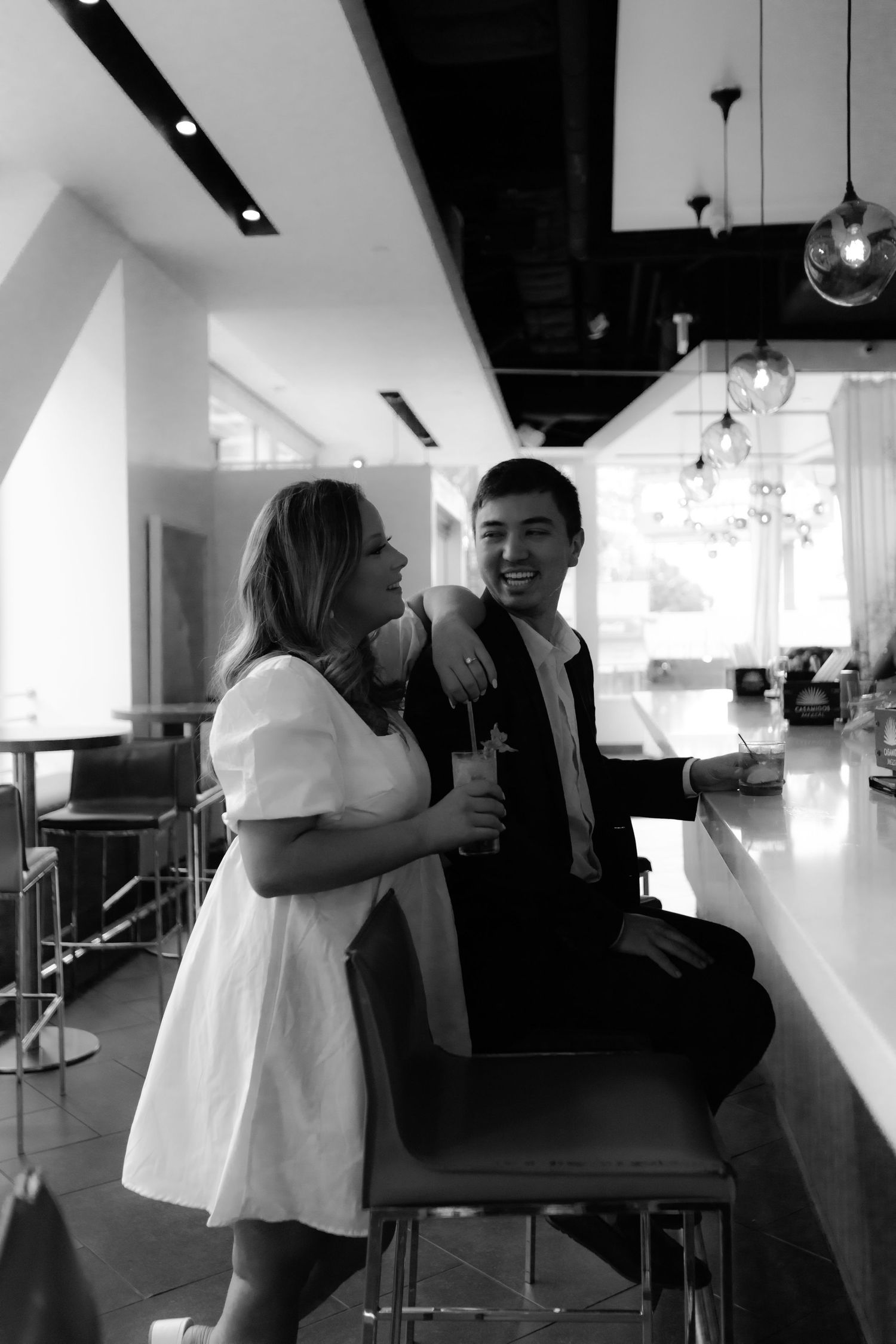 Black and white photo of happy couple laughing together at modern bar interior.