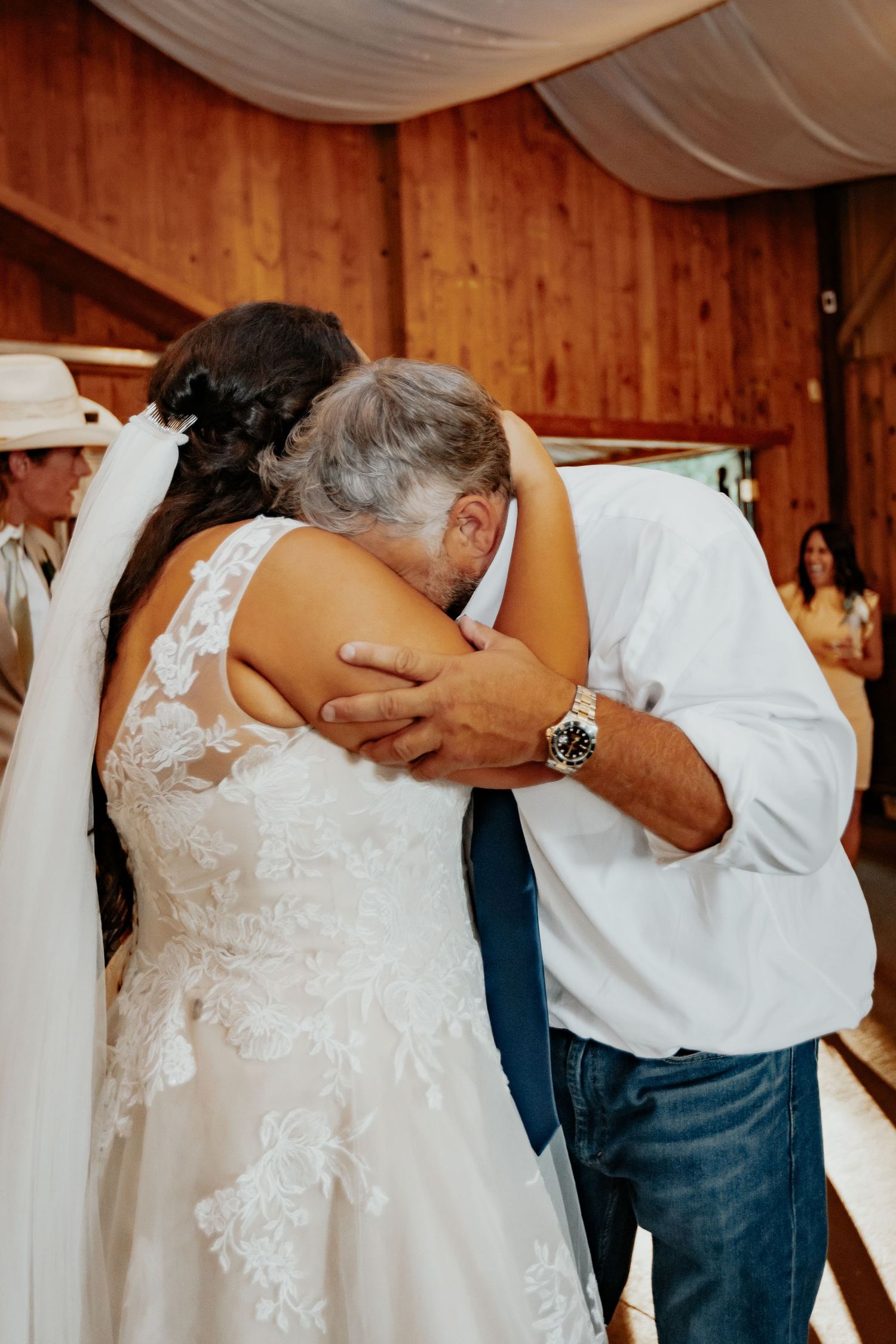 Newlywed couple kissing during a sparkler send-off wearing white outfits and cowboy hats.