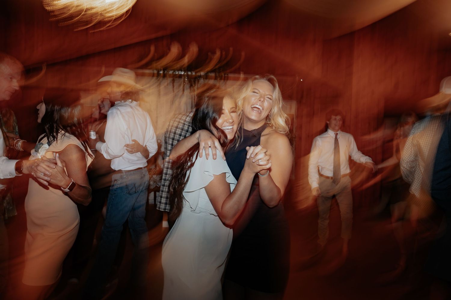 Blurred motion photo of guests dancing joyfully at a lively wedding reception.
