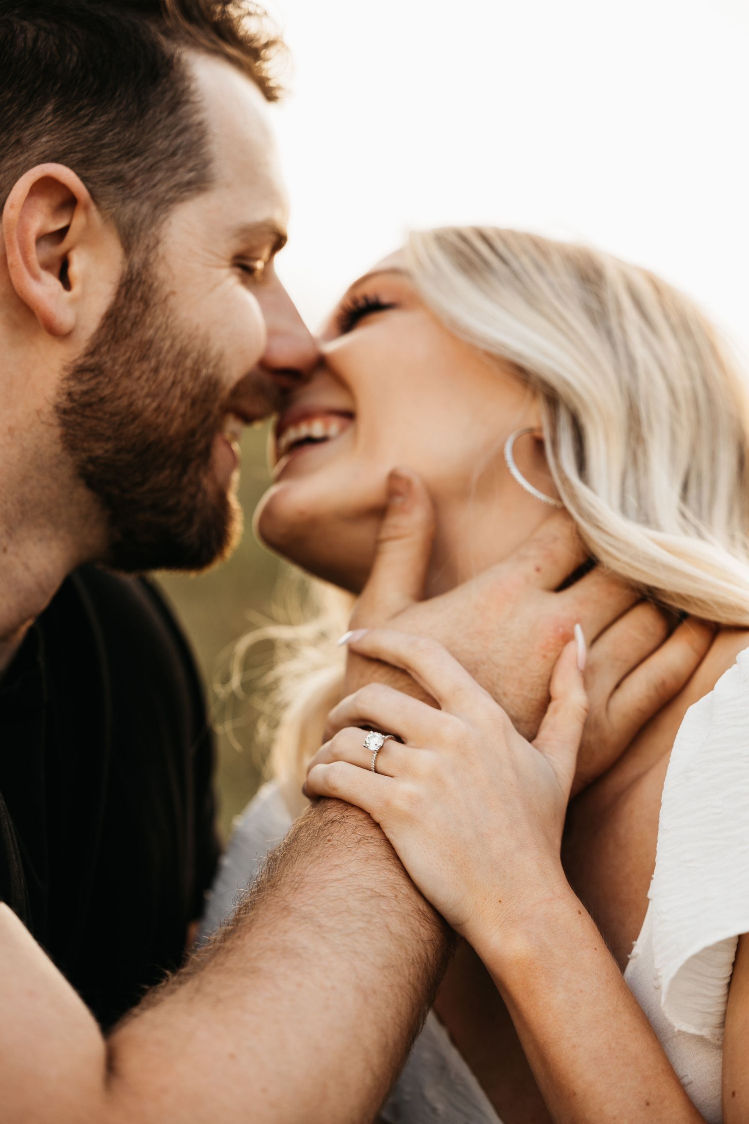 Happy engaged couple almost kissing, woman showing off diamond engagement ring.