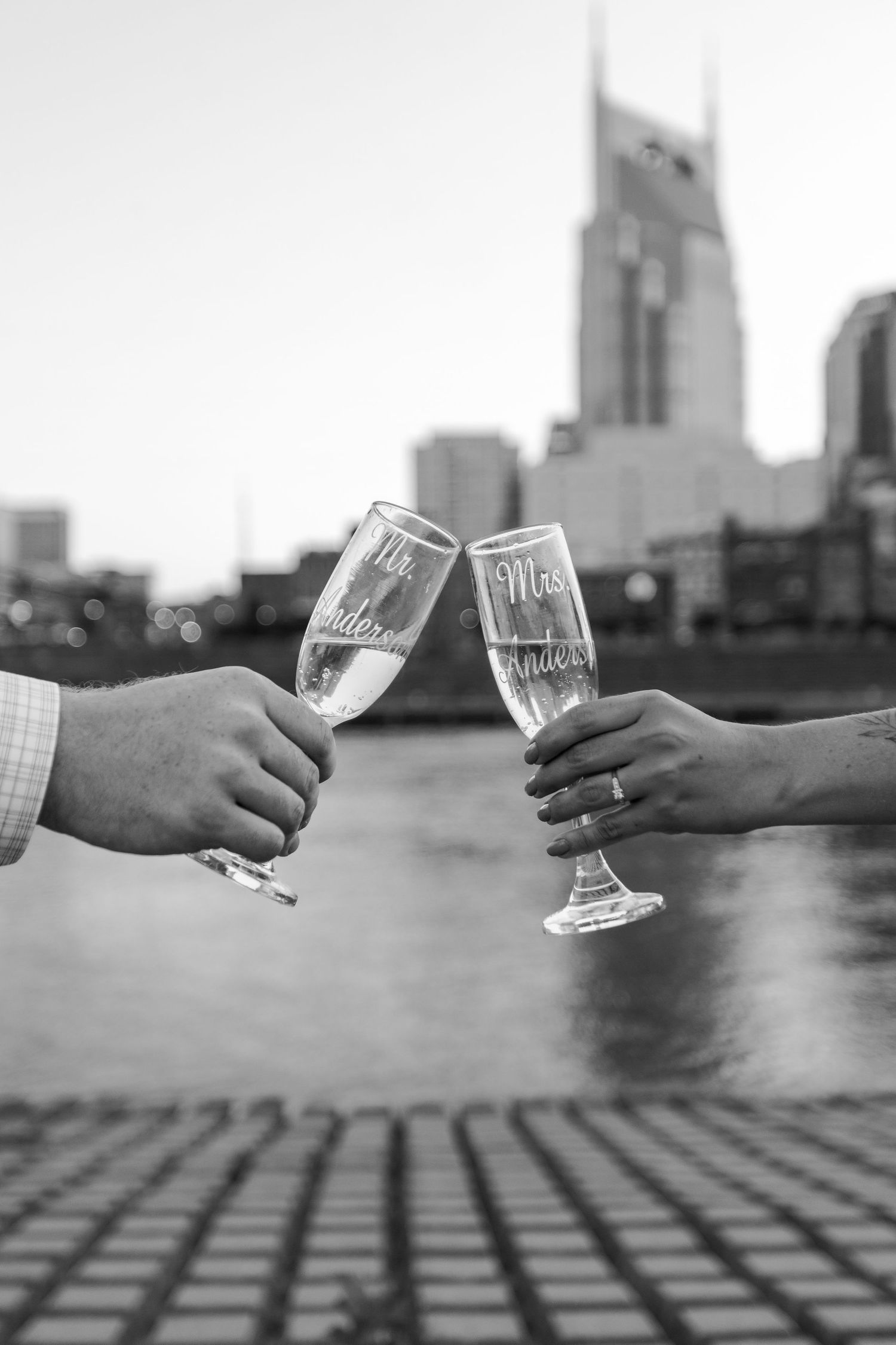 Black and white photo of Mr. and Mrs. champagne flutes toasting with Nashville skyline backdrop.