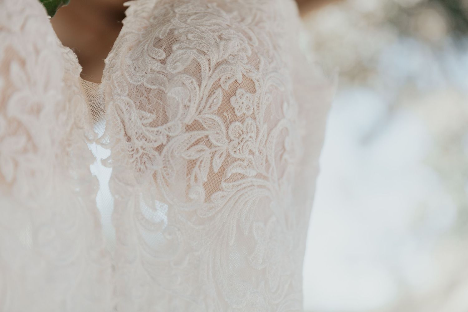 Close-up detail of intricate floral lace embroidery on a beautiful white bridal wedding gown.
