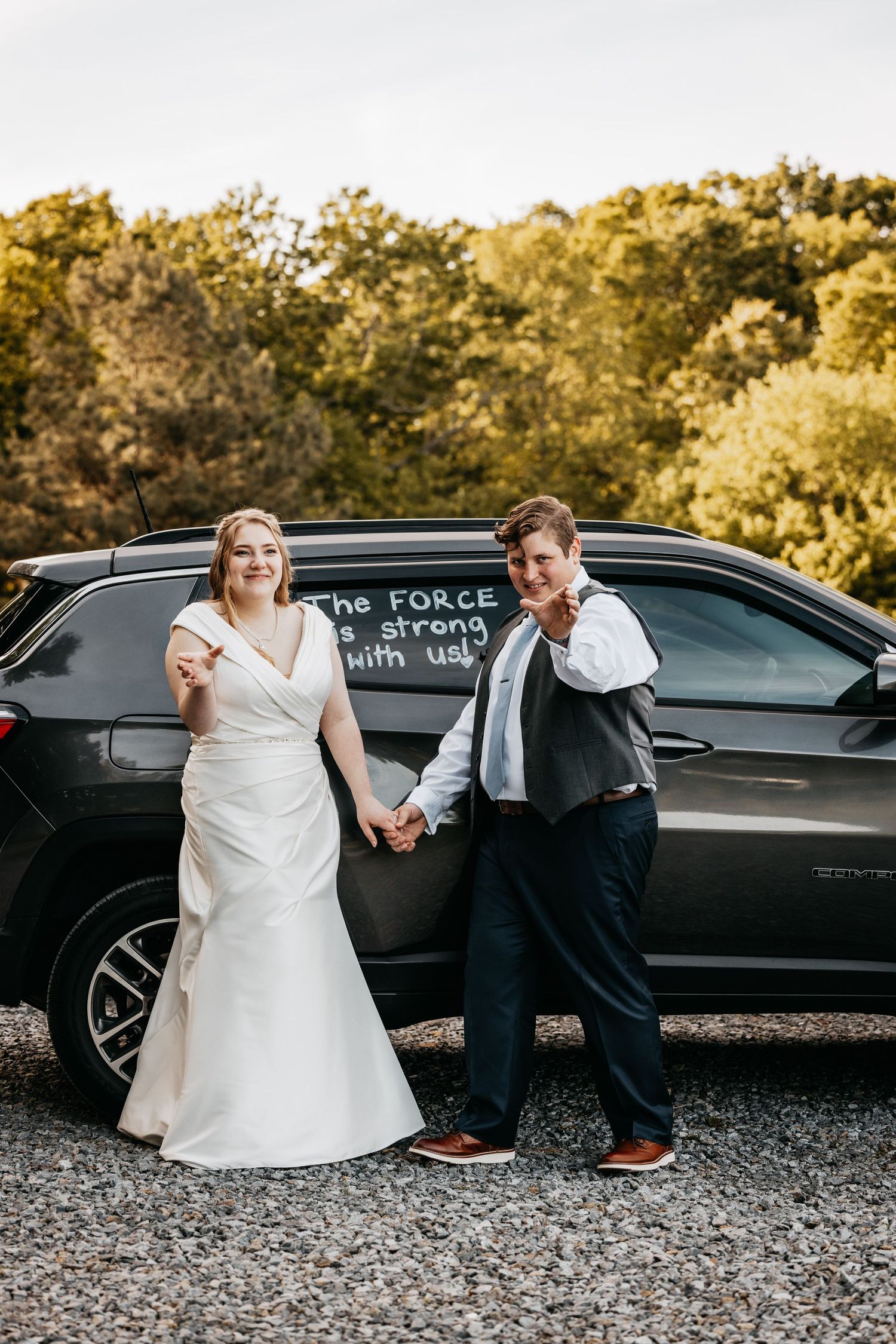 Bride and groom pose by a car with Star Wars Force quote written on the window.