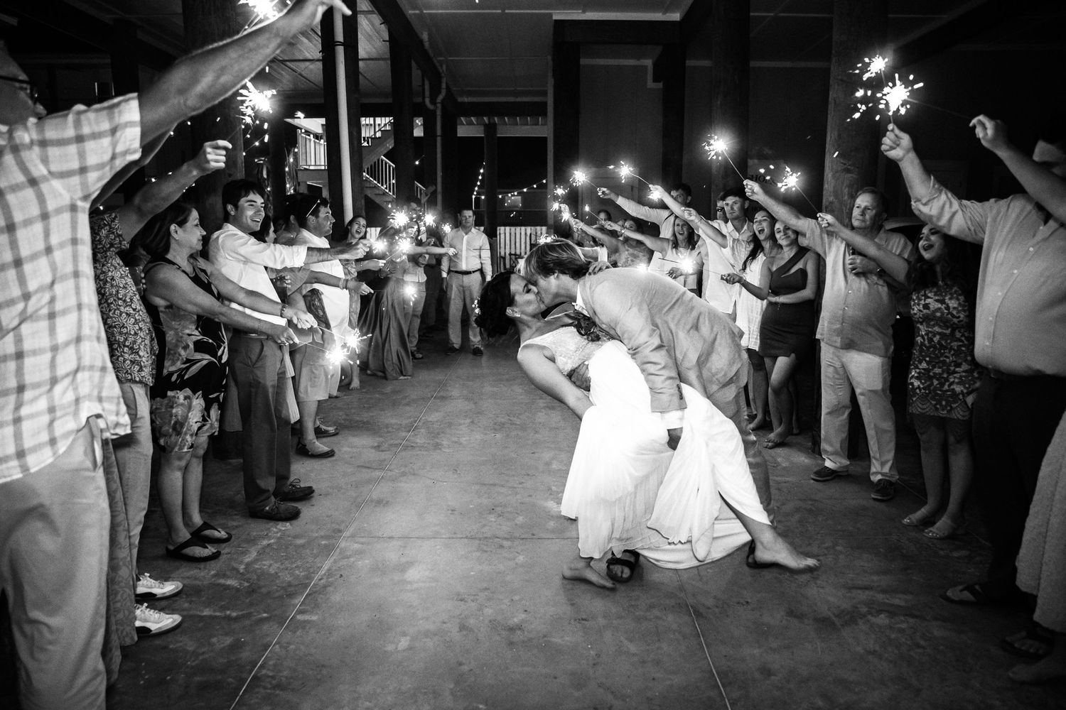 A dramatic dip during a wedding reception exit with guests holding sparklers creating a magical tunnel.