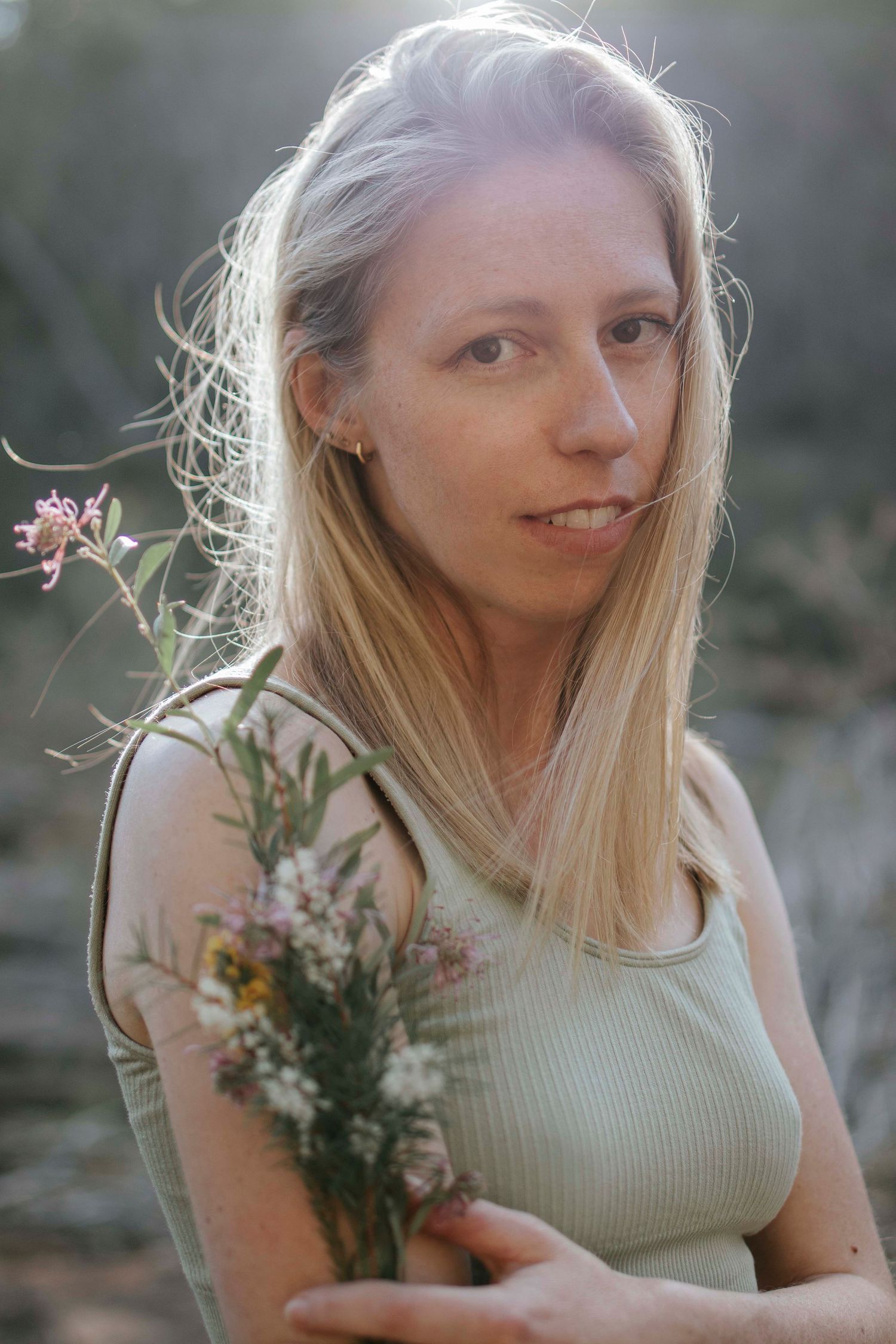 Ethereal summer portrait with wildflowers captured in golden sunlight.