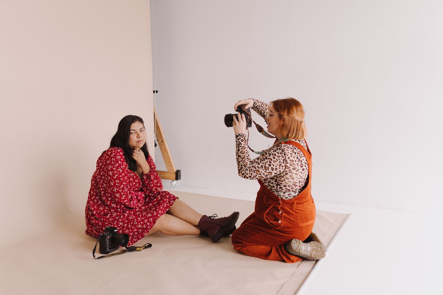 Two photographers in colorful outfits having photo session in minimal white studio.