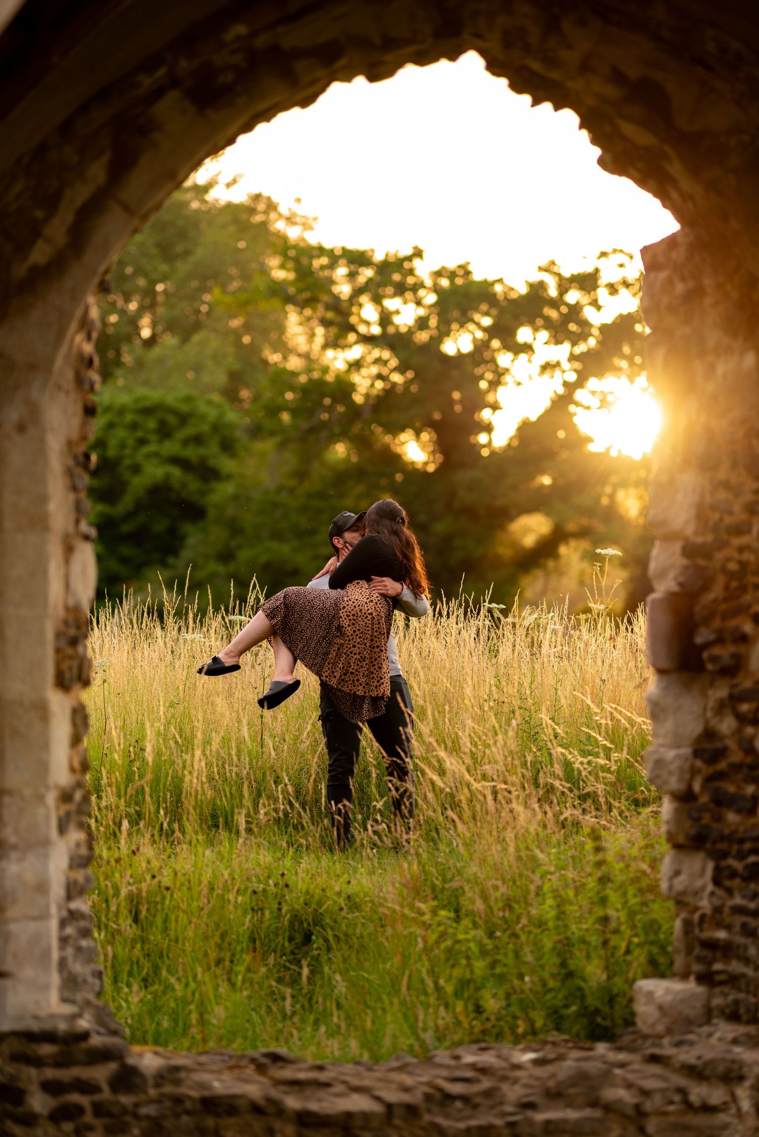 couple embracing in the sunset. Framed by the abbey ruins, old stone window. Photography, wedding, couple, engagement