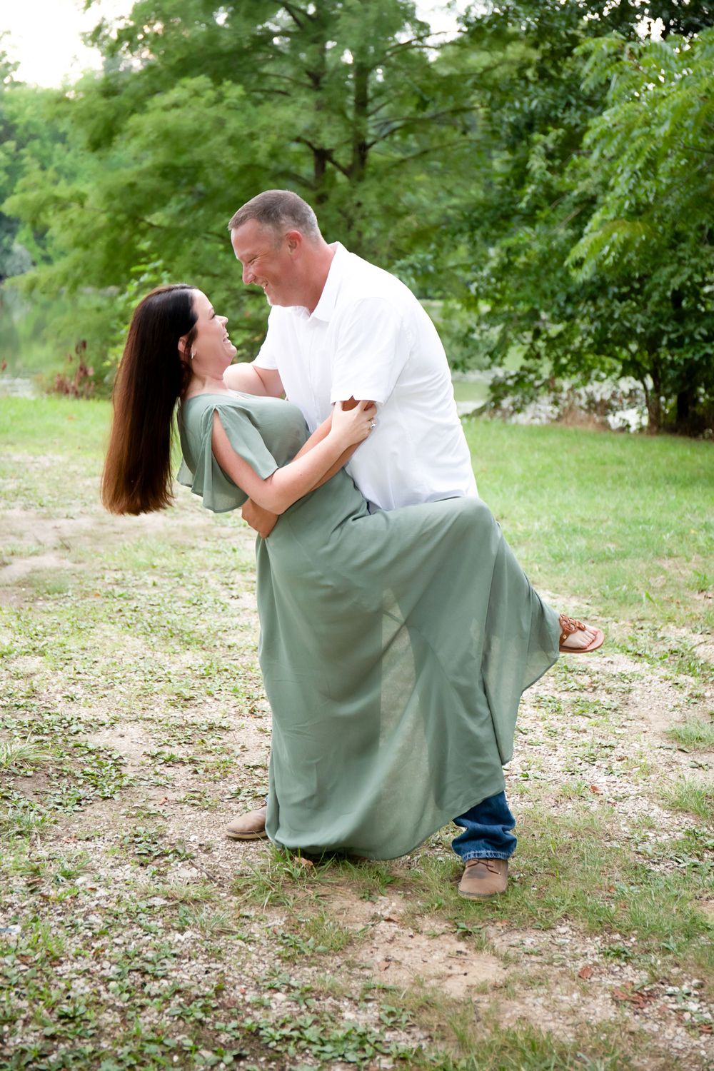 A romantic dance dip pose against a lush green outdoor backdrop.