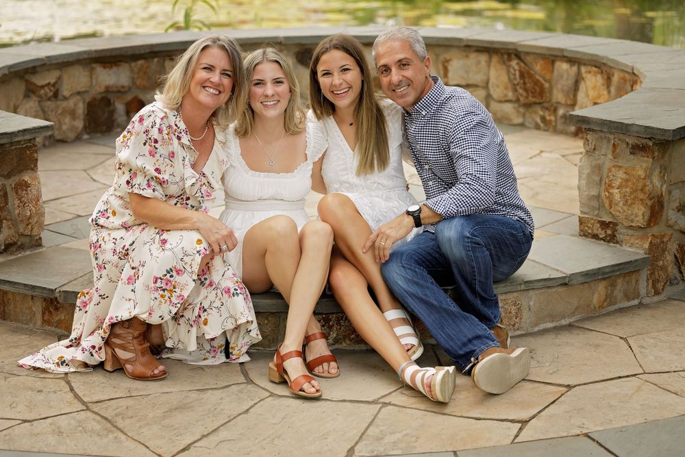 Family of four sitting together on curved stone steps outdoors.