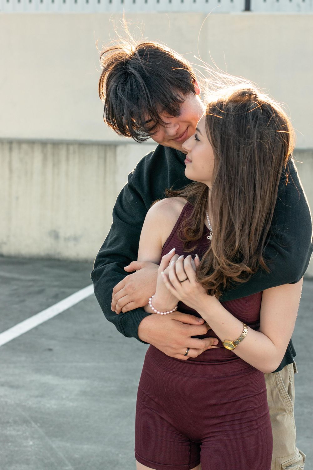 An intimate moment captured between two people in casual wear against a concrete wall.