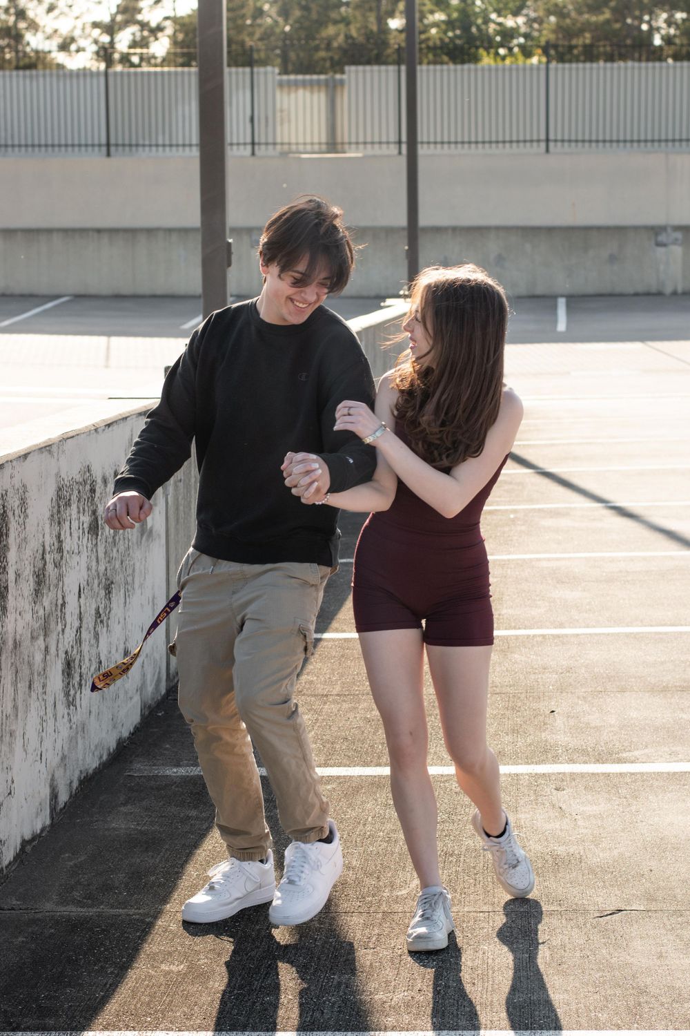 Playful couple dancing together on concrete walkway.