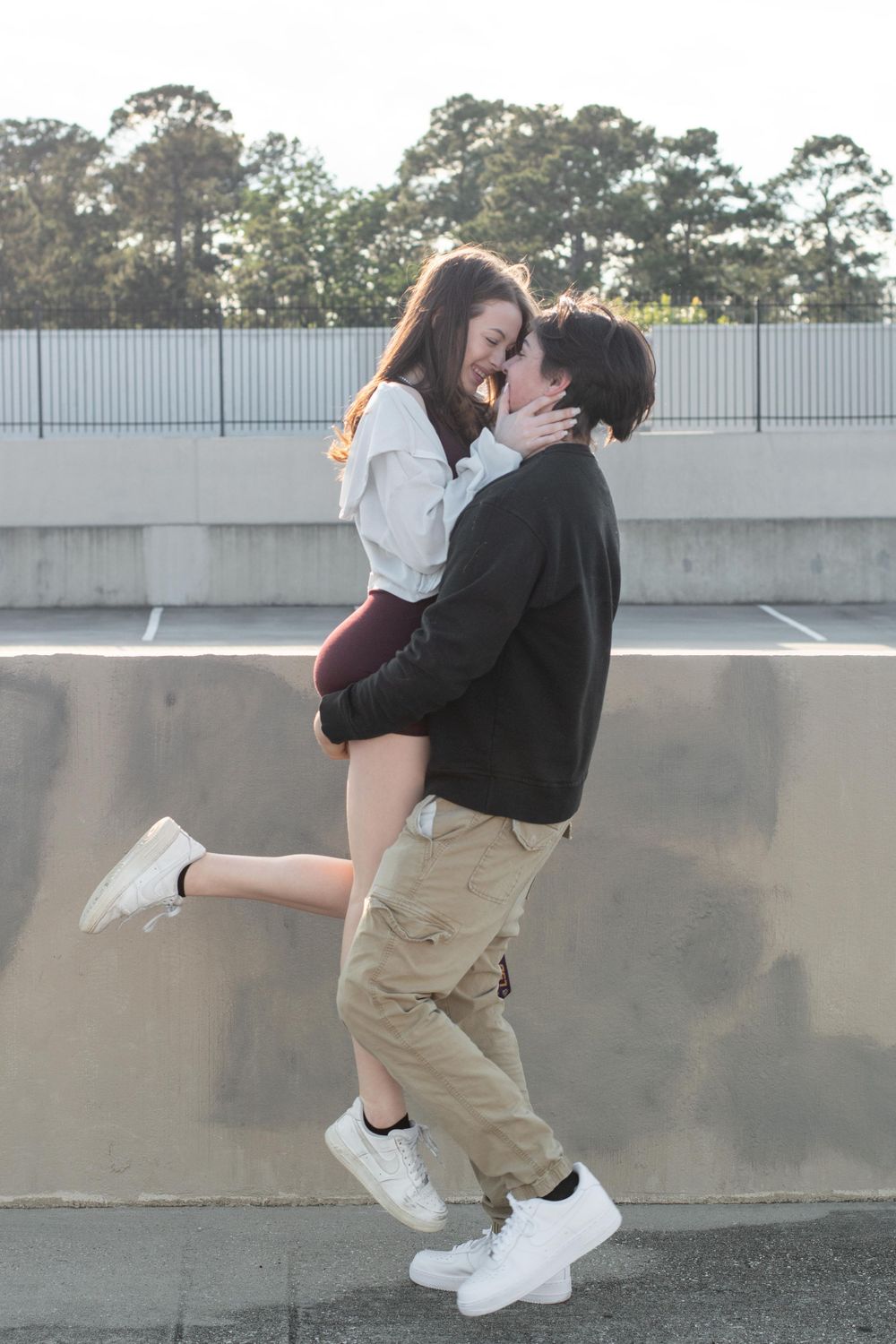 Romantic couple embracing in sunset light with parking garage backdrop.
