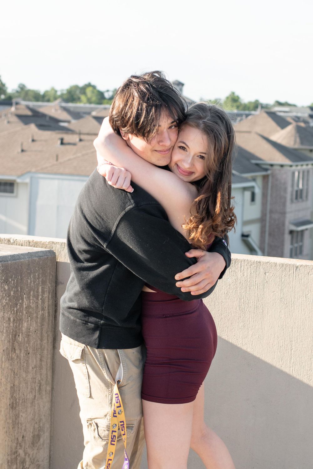 A tender embrace shared between two people against an urban rooftop backdrop.
