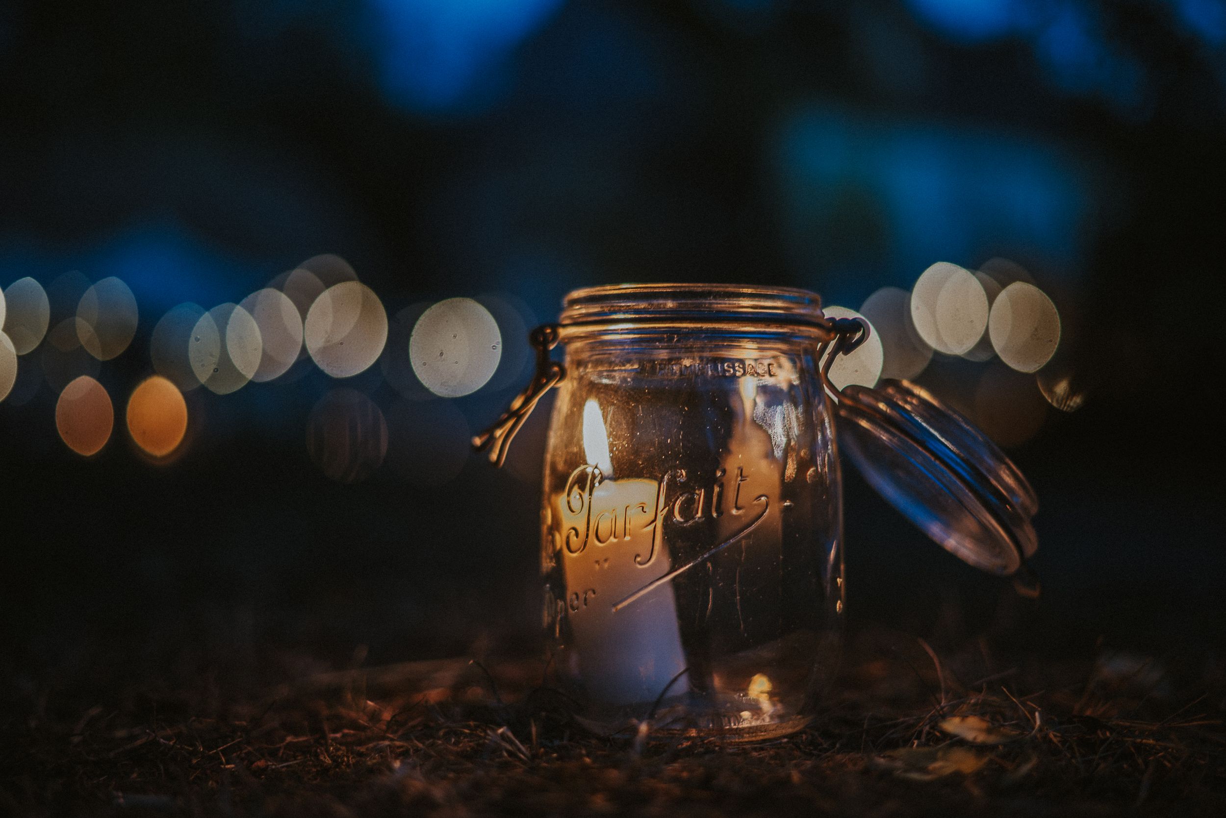 Mason jar candle holder with bokeh lights in background creating romantic ambiance.