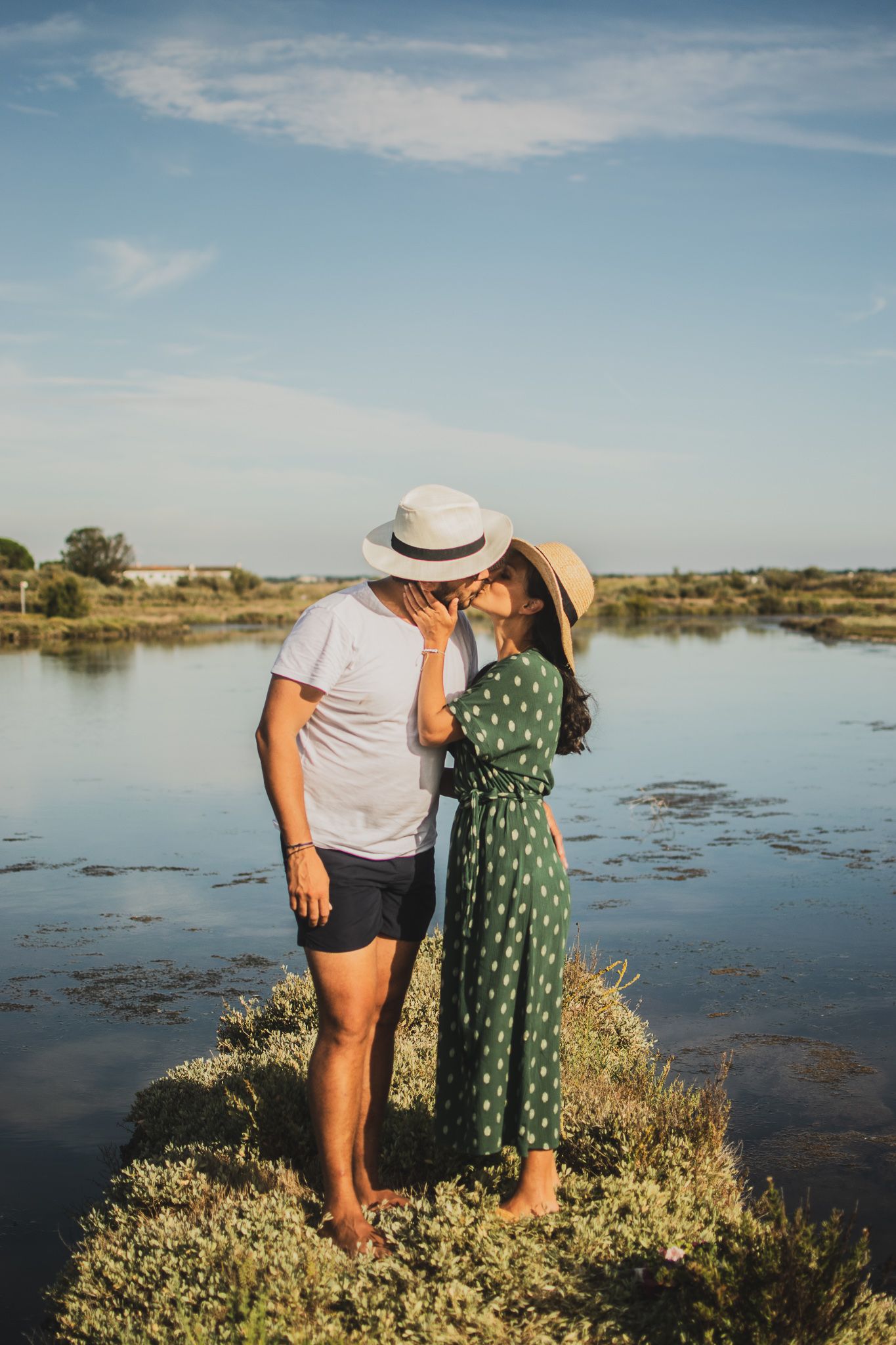 Couple in summer attire sharing an intimate moment by a lakeside.