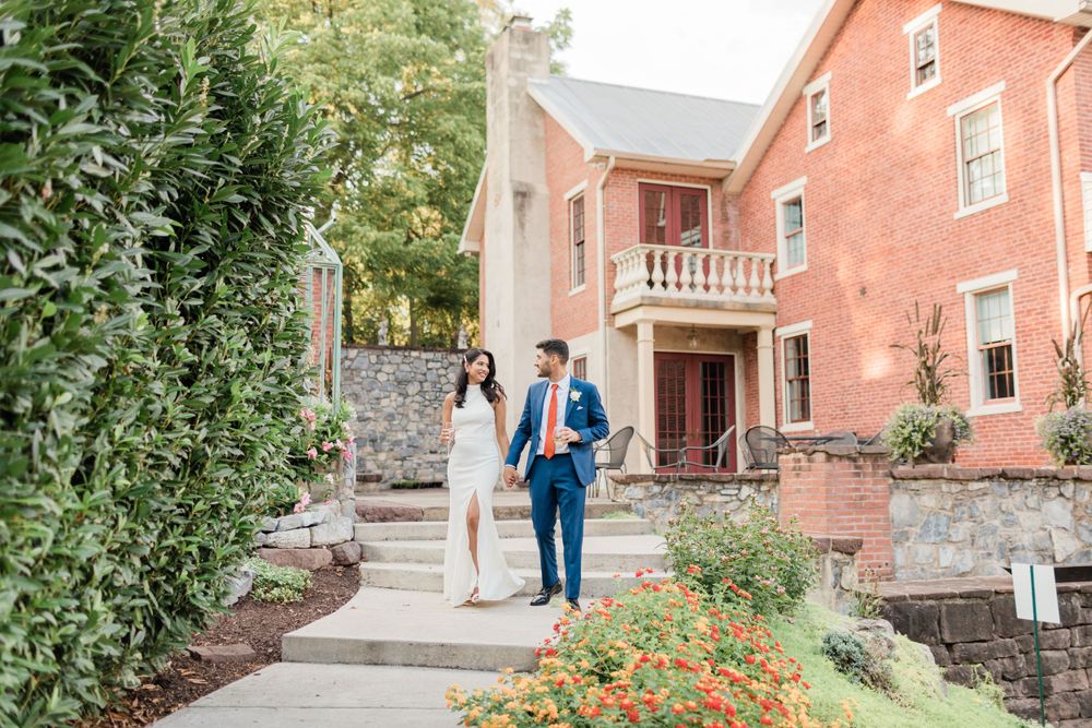 Elegant couple ascending stone steps at a brick colonial building.