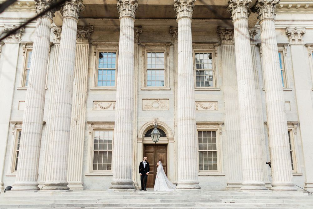 Grand courthouse wedding photo with towering classical columns and architectural details.