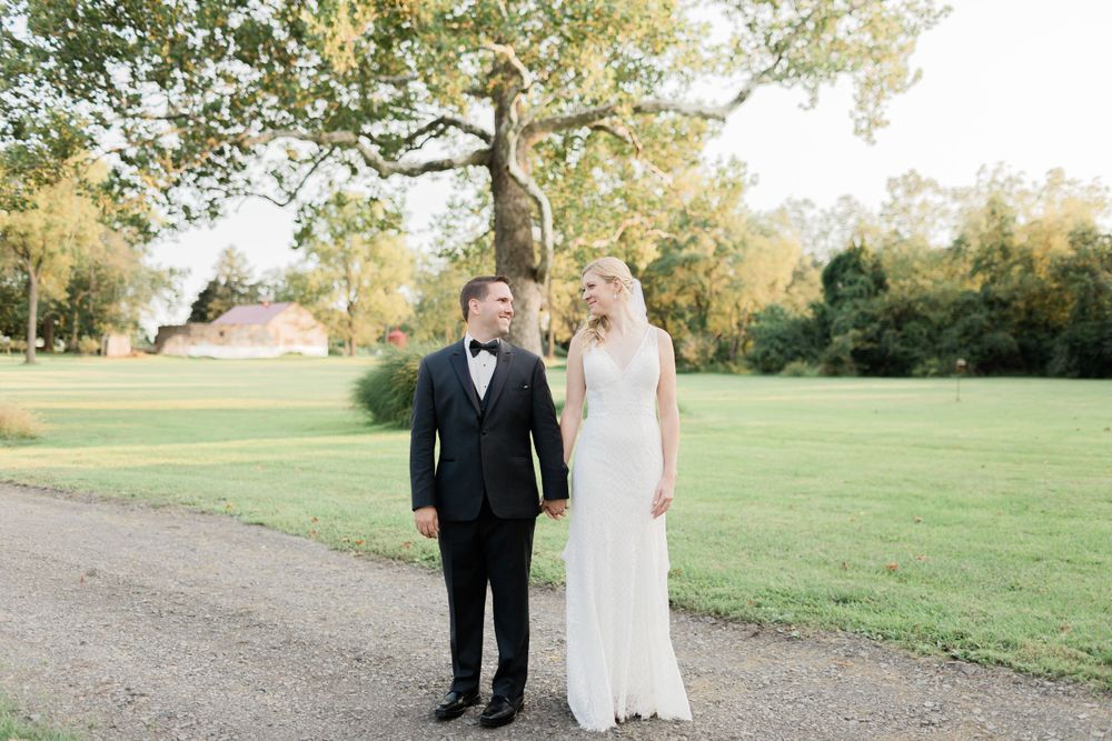 Formal wedding portrait on a gravel path with lush green garden background.
