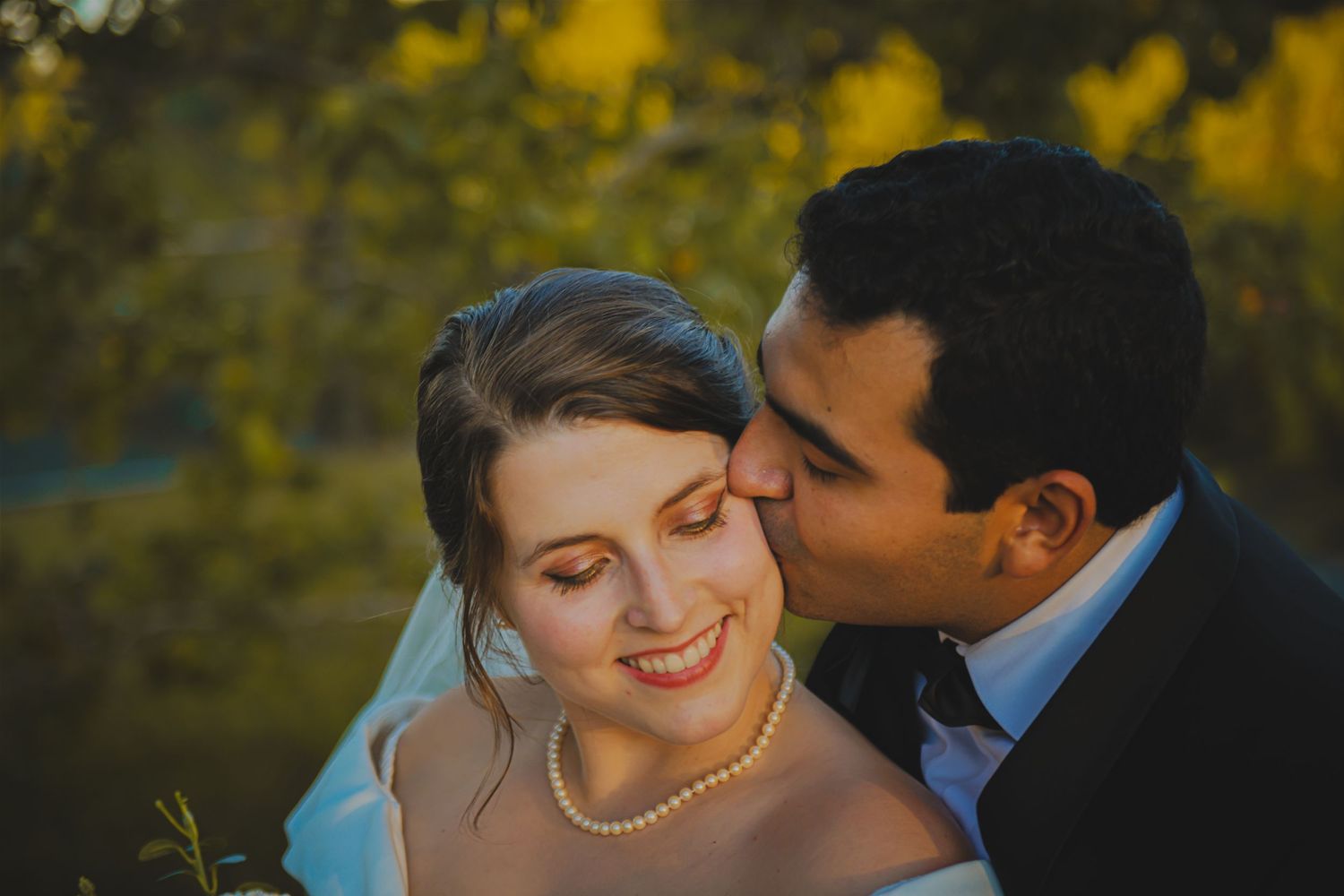 Groom Kissing Bride on the Cheek Smiling Wedding Portrait