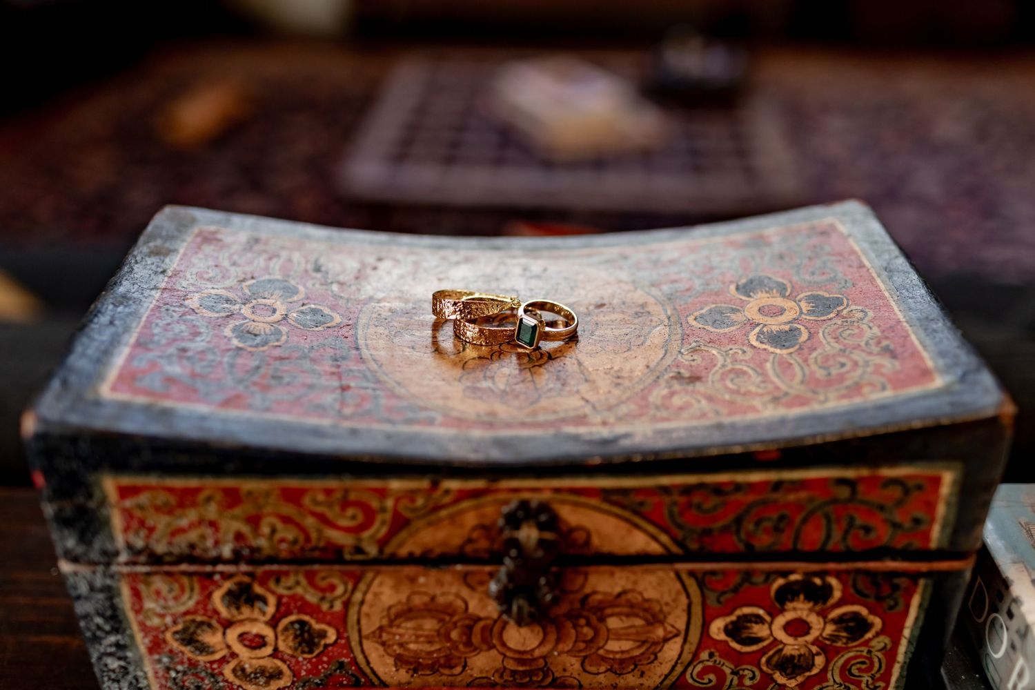 Two gold wedding rings sitting on top of an ornate vintage decorative box.
