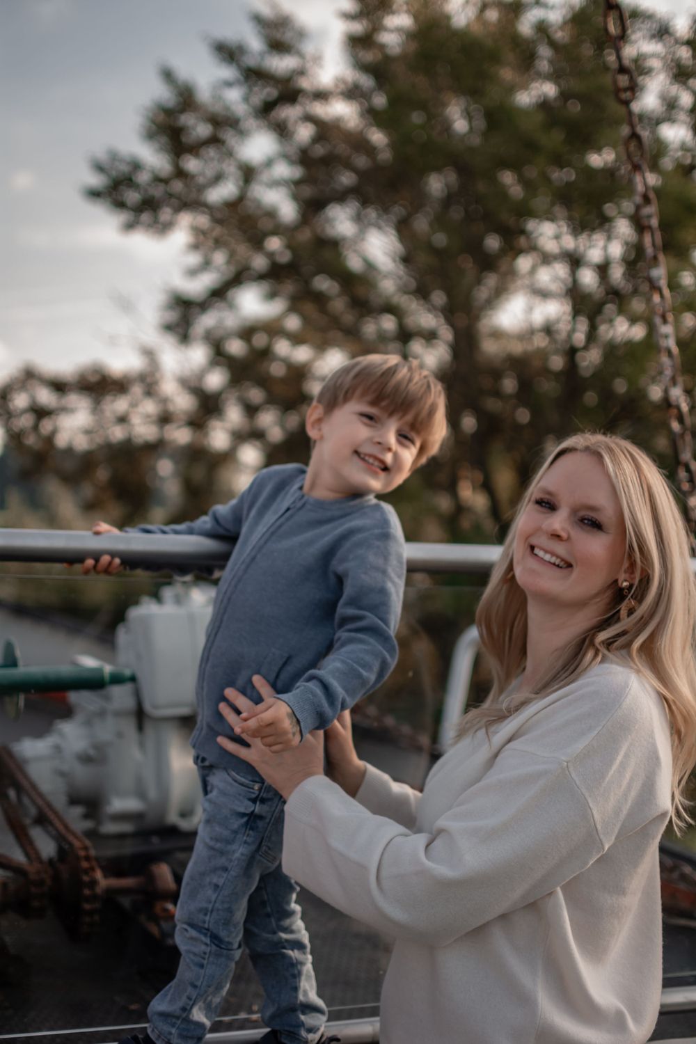 A playful outdoor moment captured between parent and child wearing cozy sweaters on a cloudy day.