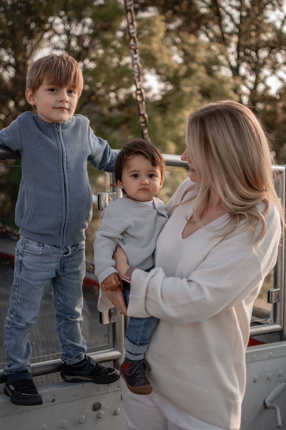 A family moment at a playground with two children and an adult in casual attire.