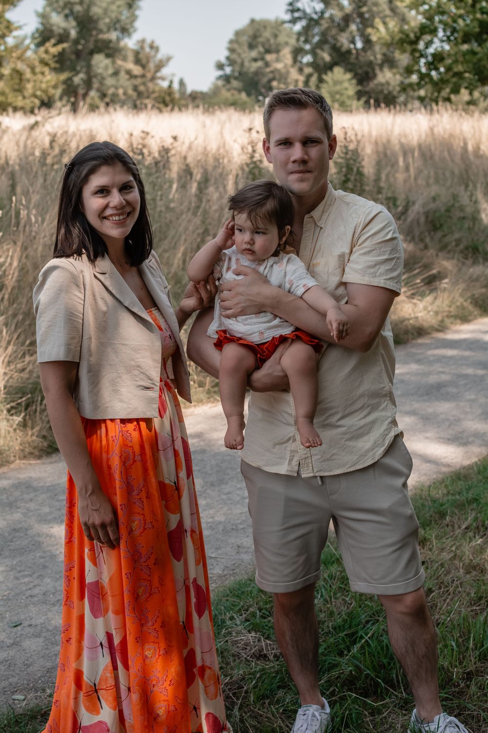 A family portrait in nature featuring coordinated neutral tones and a bright orange floral skirt.
