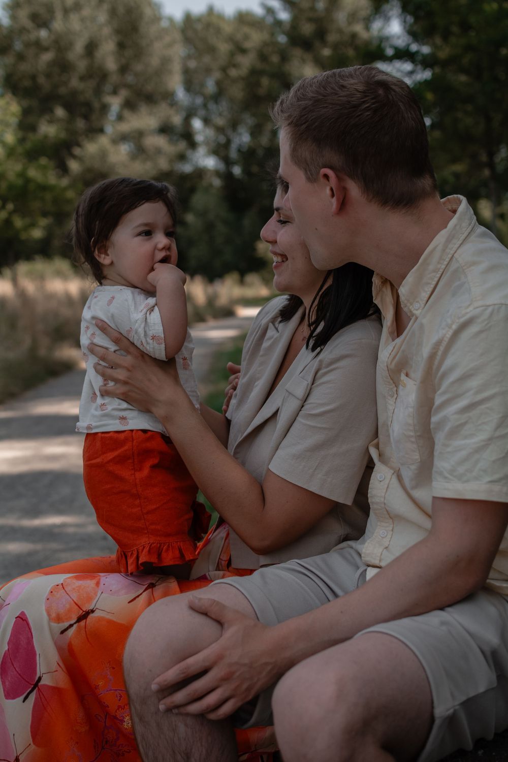 An intimate family moment captured outdoors on a sunny afternoon.