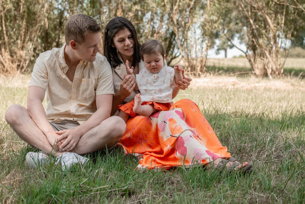 A relaxed family scene on grass with bright orange clothing accents.