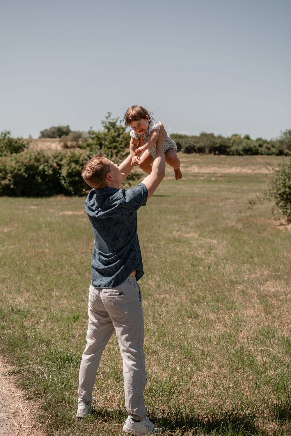 A joyful moment of a parent lifting a small child high in the air outdoors.