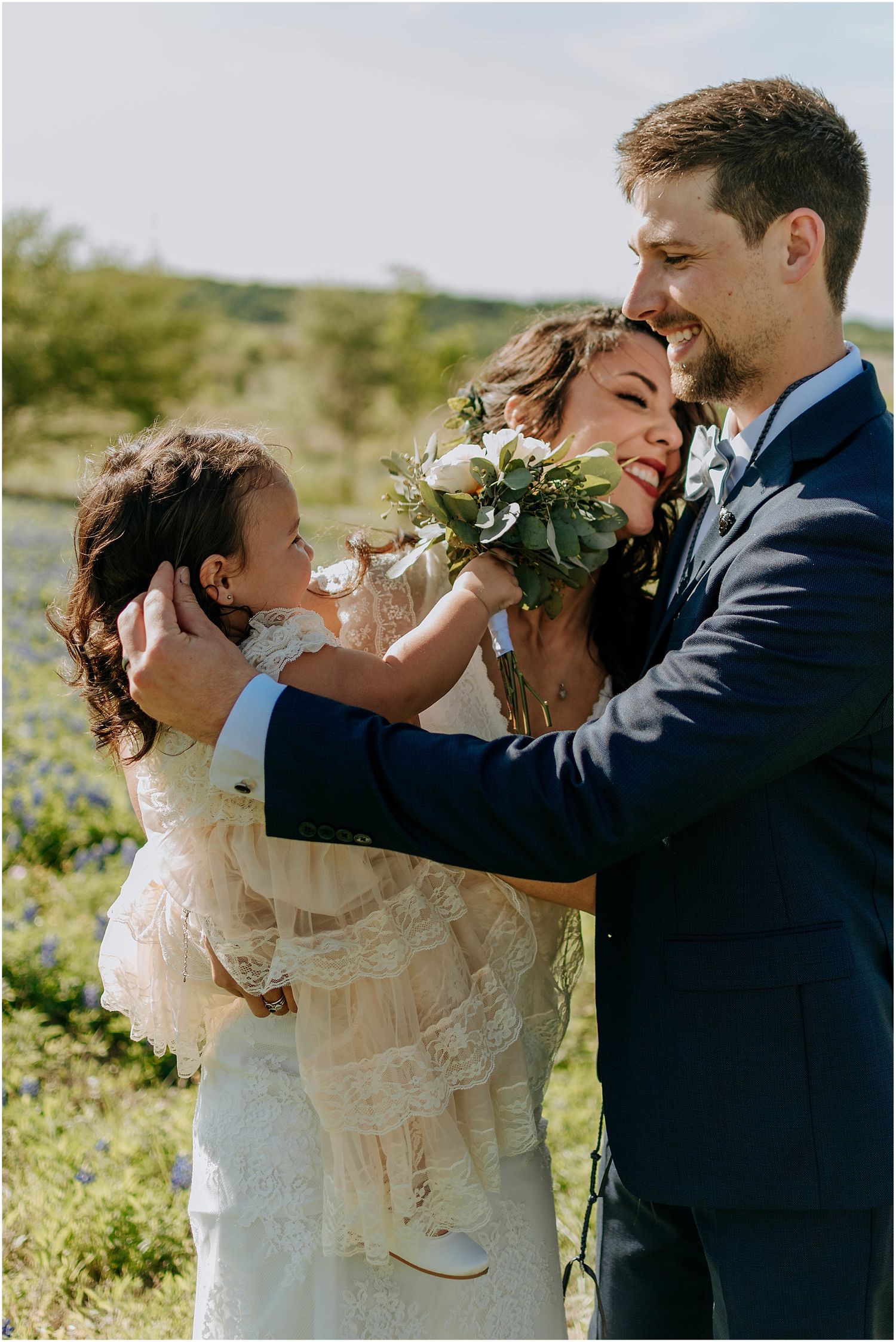 Intimate family moment captured during outdoor wedding celebration.