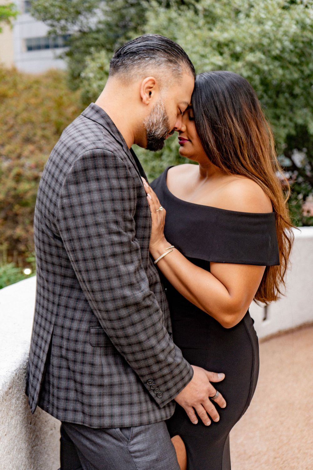Romantic couple in elegant black and plaid outfits sharing intimate moment outdoors.