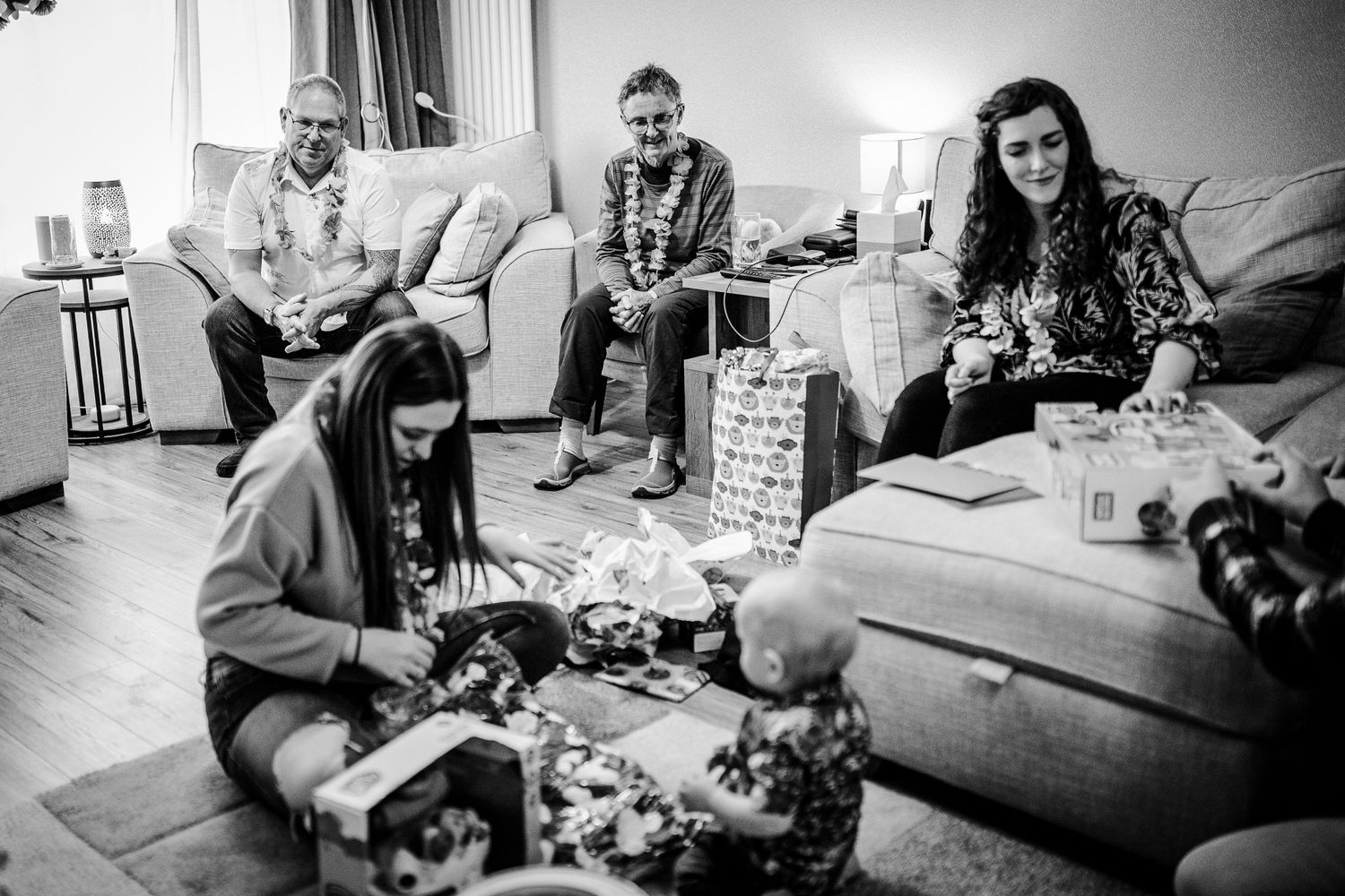 black and white photo with great grandmother, grandad and mother watching the birthday boy open his presents