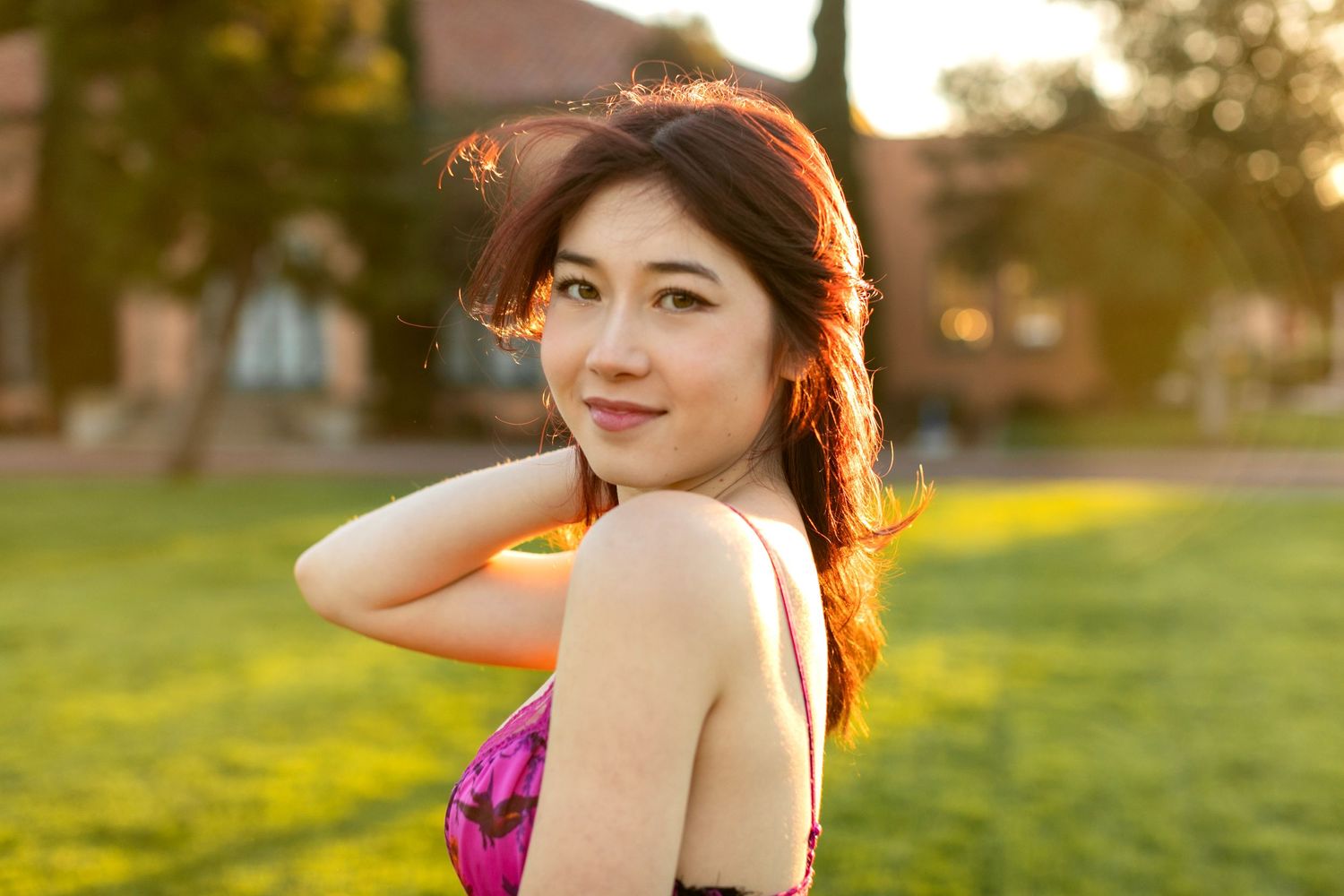A high school senior in magenta top with sunset lighting in park setting.