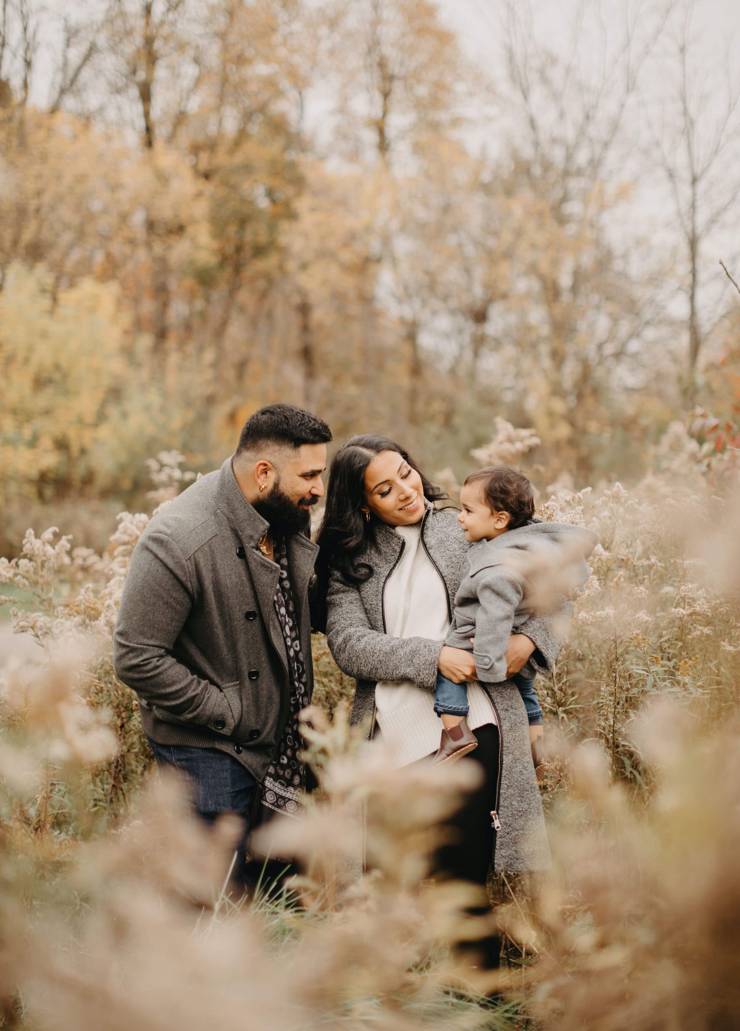 Family enjoying tender moments together in an autumn setting with golden foliage.