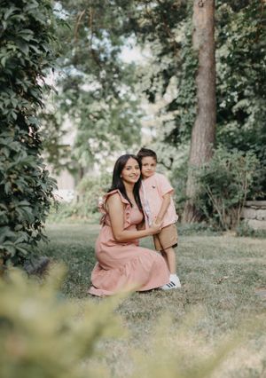 Couple in matching pink outfits sitting together on grassy hill among trees.