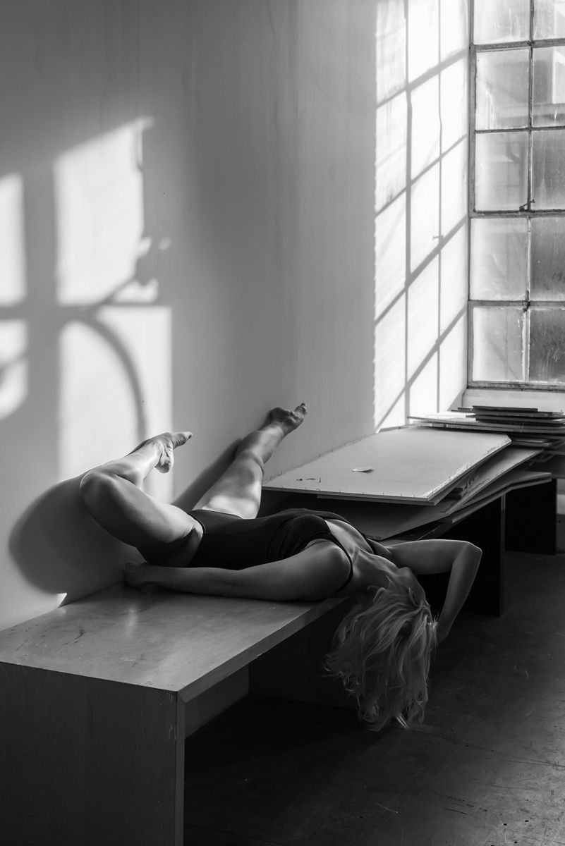 Artistic black and white photo showing a reclining silhouette by a sunlit window.