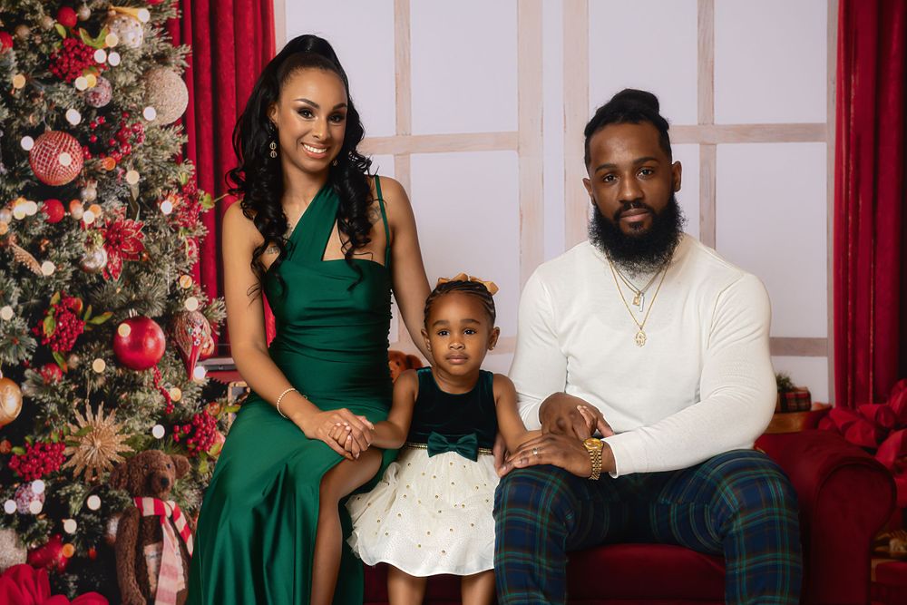 Elegant family Christmas portraits with emerald green dresses and white decor against decorated tree.