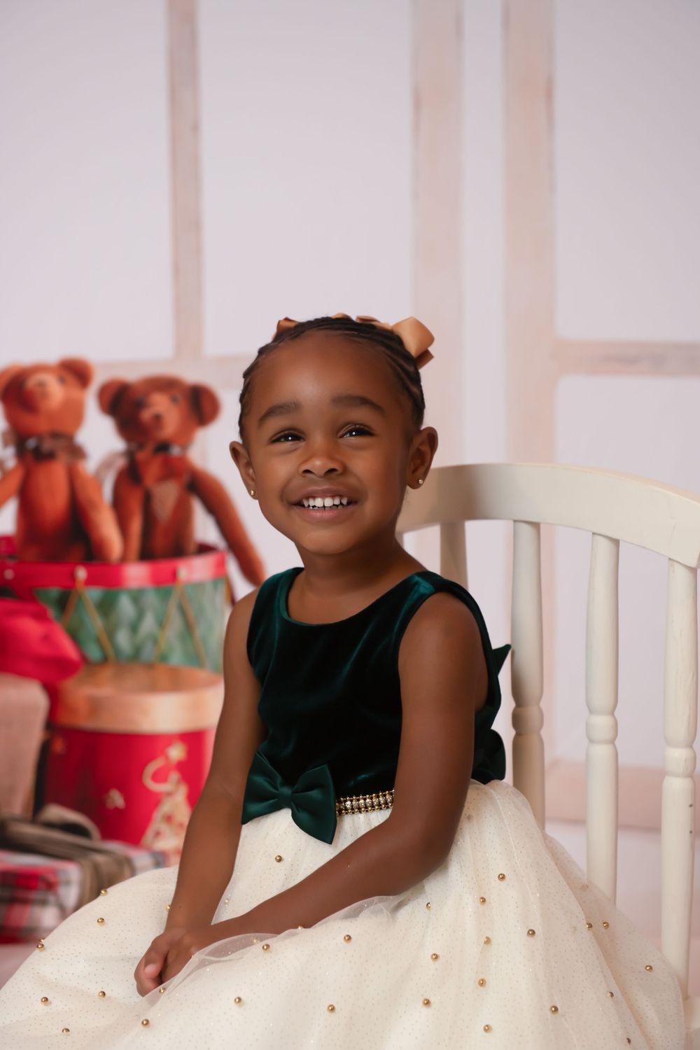 Studio portrait session with white backdrop and festive holiday teddy bear decorations.