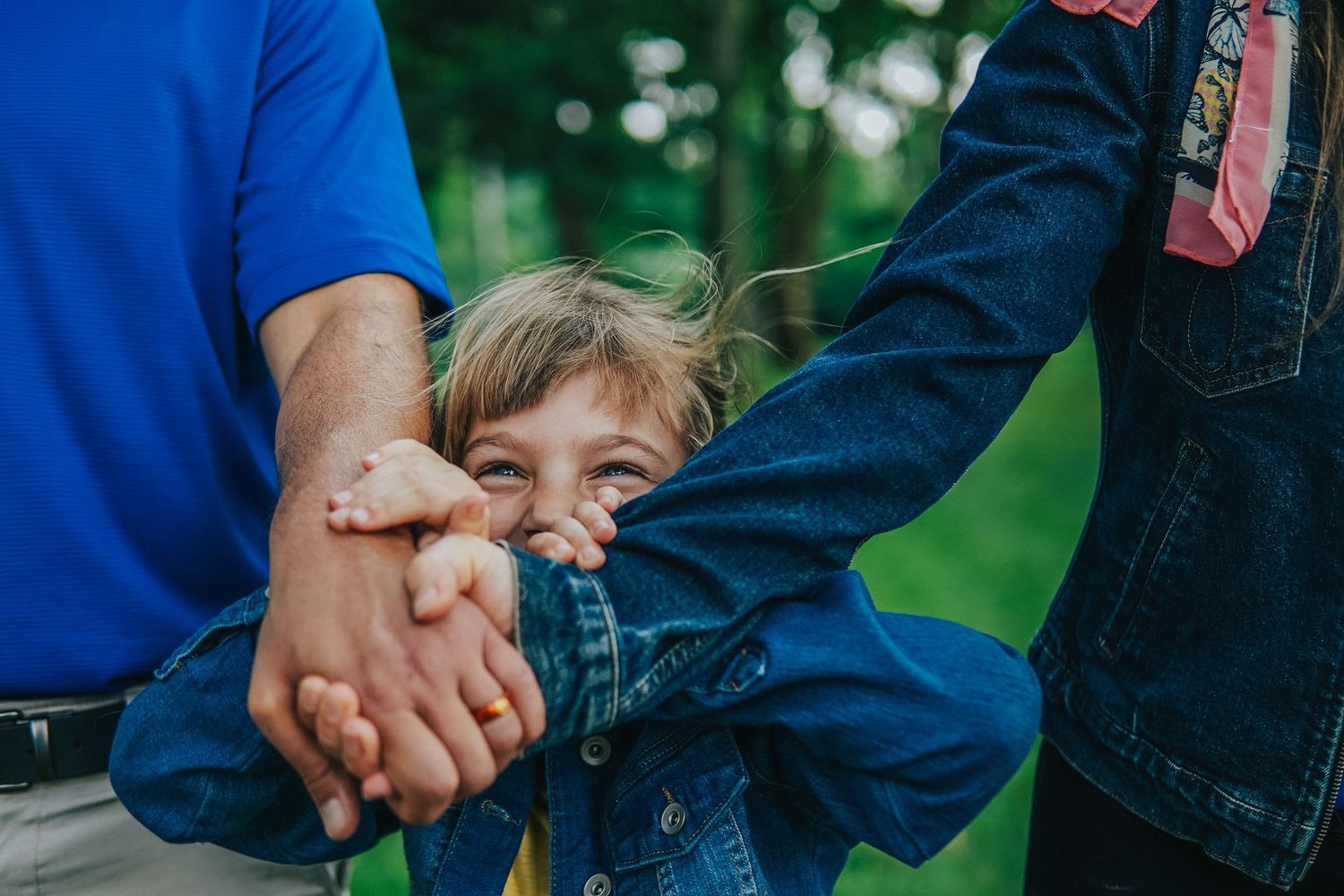 Close-up photo of holding hands outdoors against a blurred green background.