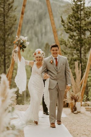 A bride and groom celebrate while walking down the isle after getting married in Winter Park Colorado