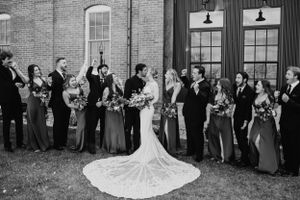 A bride and groom kiss while surrounded by their bridal party