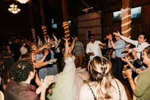 A bride celebrates on the dance floor surrounded by guests