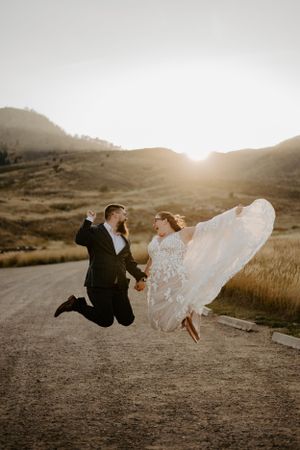 A bride and groom jump in excitement during their wedding in Lory State Park