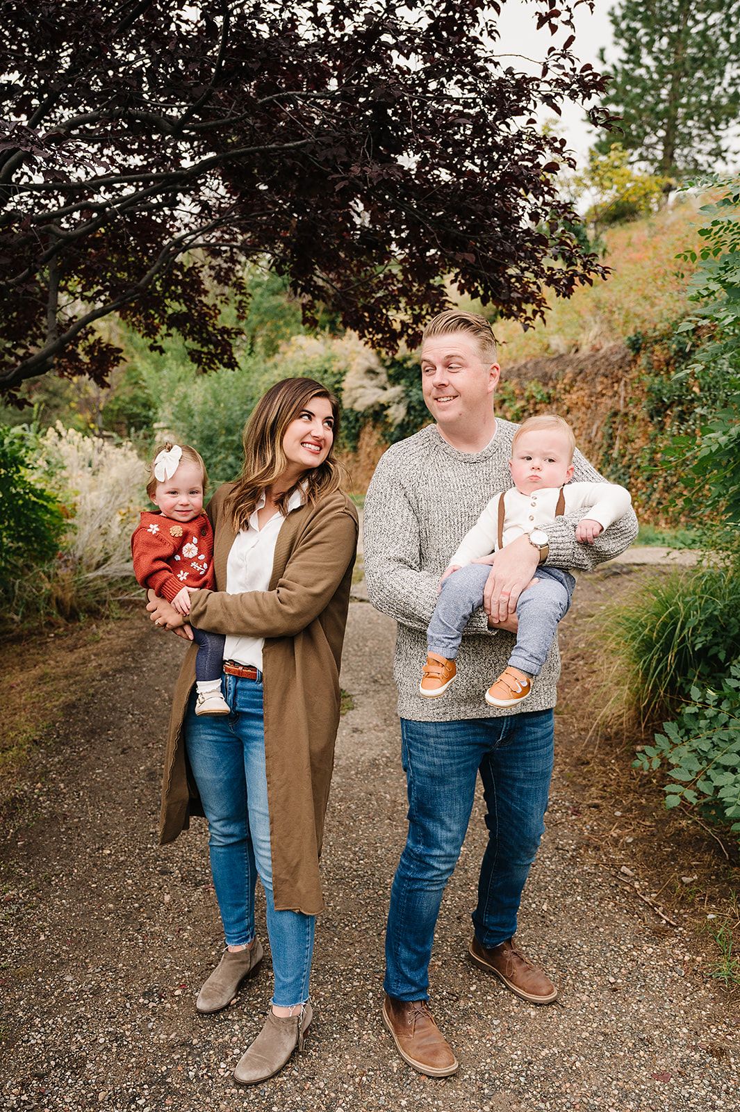 A family of four walking together on an autumn path.